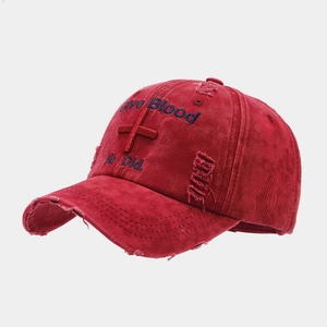 Close-up of distressed red baseball cap with vintage embroidery and cross detail