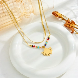 Detail of a gold layered necklace featuring colorful beads and a sunburst fan pendant