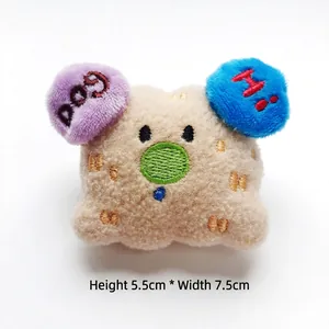 Detail of plush dog accessory with DOG and HI embroidery, size 5.5cm by 7.5cm