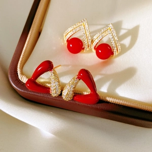 Détail de boucles d'oreilles triangles plaquées or 18k avec résine rouge et zircon