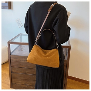 Rear view of model wearing a caramel suede hobo bag with adjustable metal buckle strap