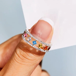 Detailopname van een zilveren ring met kleurrijke vierkante stenen en pavé diamanten randen
