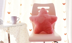 Detailed view of pink star-shaped plush pillow on chair in a cozy sunlit room