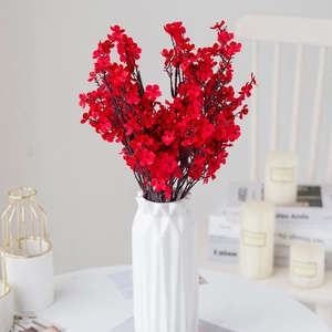 Close-up of artificial red flowers in a white geometric ceramic vase for home decor