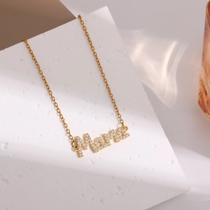 Detail of gold MAMA letter necklace pendant with sparkling rhinestones on display