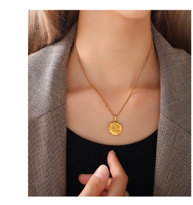 Close-up of minimalist daisy flower embossed gold pendant necklace worn on neck