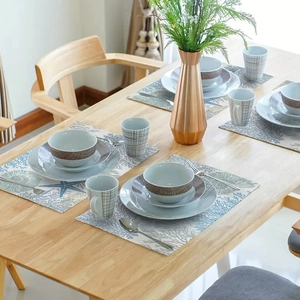 Overhead view of blue coral placemats and ceramic tableware on a wooden dining table