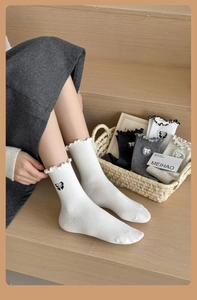 Detail of white mid-calf socks with delicate lace trim and embroidered bow accents