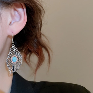 Detail view of vintage leaf earrings with turquoise stones on a model in side profile