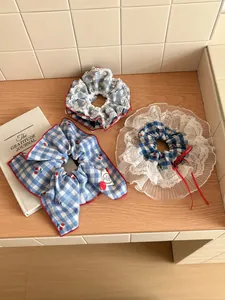 Detail of blue plaid hair accessories with cherry prints, lace trim and red ribbons