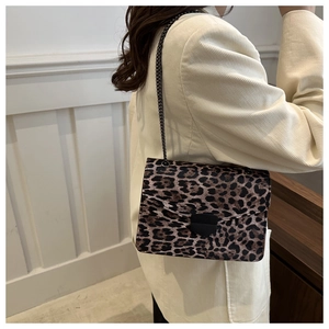 Detailed side view of a leopard print crossbody bag with black metal chain and flap