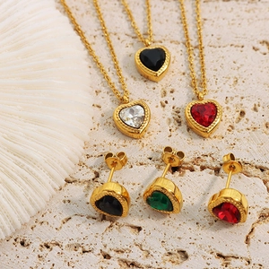Gold-plated jewelry set with heart-shaped colorful zircons on a textured stone background