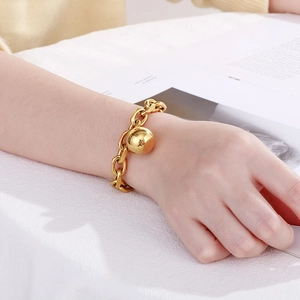 Fashionable gold stainless steel chain bracelet with large hollow metal ball on model's wrist