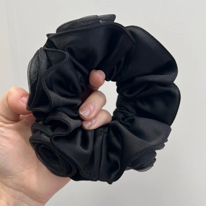 Detail of a large black satin scrunchie with layered fabric and mesh texture for women