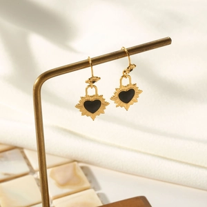 Vue détaillée des boucles d'oreilles cœur doré avec rayons sur un support à bijoux