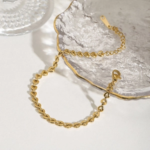 Elegant gold hollow heart-shaped woven link bracelet on a decorative glass tray