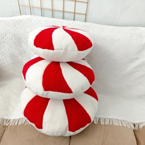 Three-piece red and white striped peppermint Christmas plush pillows on white sofa