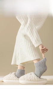 Close-up of gray coral fleece socks and plush slippers with soft, warm fabric texture
