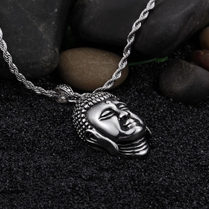 Detailed close-up of silver Buddha head pendant with rope chain on black stones