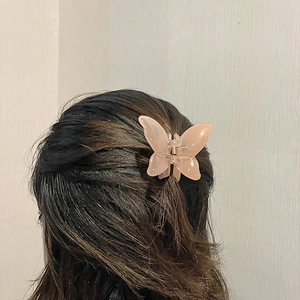 Detail of a translucent pink butterfly claw clip styled on long hair for a feminine look