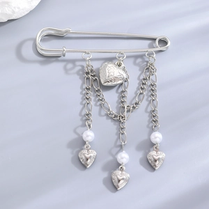 Detailed view of silver heart pin brooch with hanging chains and faux pearl accents