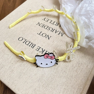 Detail of yellow fabric headband with cartoon cat charm and pearl bead bow accessory
