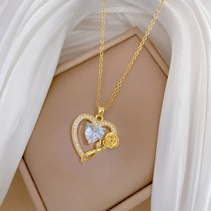 Golden heart pendant necklace with crystal accents and rose detail on silk fabric