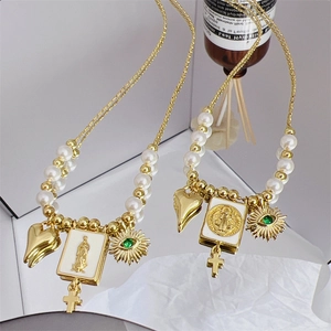 Collier doré 18 carats avec perles, charms cœur et œil posé sur une surface à effet miroir