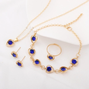 Detail shot of golden heart jewelry set with blue crystal inlays on a white tray