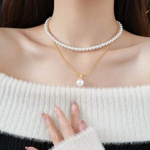 Close-up of double layer necklace set featuring white pearls and gold round pendant