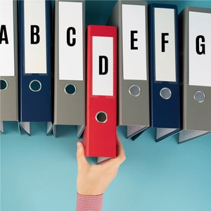 Overhead view of colorful lever arch files with alphabetical labels on blue surface