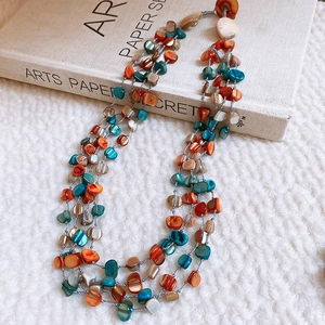 Detailed close-up of multi-layer beaded necklace with colorful shell and stone beads