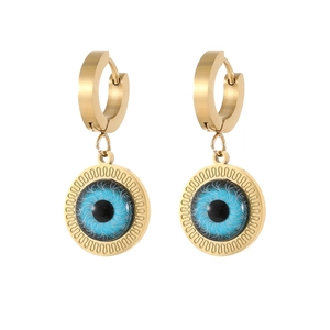 Detail view of golden hoop earrings featuring blue evil eye charms and polished metal