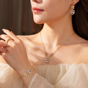 Close-up of elegant gold jewelry set with purple gemstones and zircons on a model