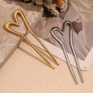 Macro shot of 18K gold and silver plated double-prong heart hair pins on textured stone