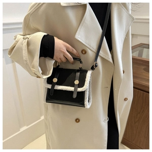 Close-up of luxury crossbody bag with black texture and white faux fur trim on model