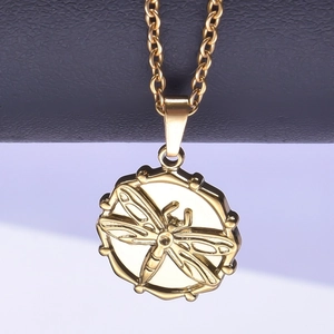 Macro shot of a golden dragonfly embossed circular pendant on a sleek metal chain