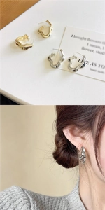 Détail de boucles d'oreilles irrégulières en métal fondu avec texture de vague