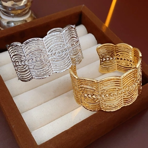 Detail von wellenförmigen Armreifen in Gold und Silber auf einer braunen Samtbox