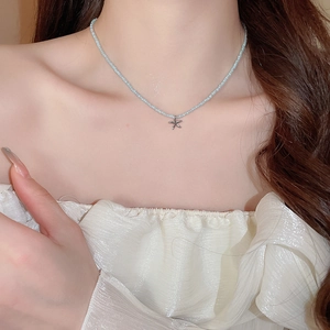Detail of light blue beaded necklace featuring a silver starfish pendant on neck