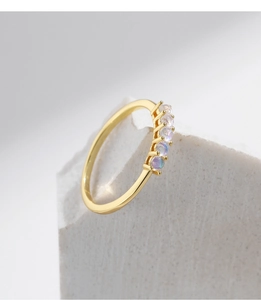 Detailed shot of a thin gold ring featuring five small round iridescent moonstones on stone