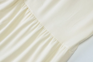 Macro shot of off-white fabric texture with pleated details and elegant gathered seams