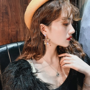 Close-up of dangling star earrings with diamonds on a model for a chic look