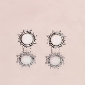 Detailed macro shot of vintage sun-shaped silver earrings with opal and crystal inlay