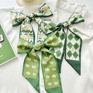 Green silk-like scarf set with floral and geometric patterns on a white shirt