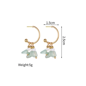 Detailed view showing C-shape gold earrings with white beads and green stones