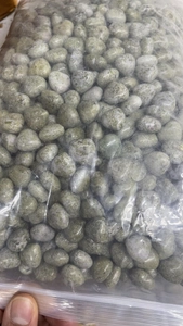 Macro detail of 15mm green and gray heart-shaped natural crystal stones in clear bag