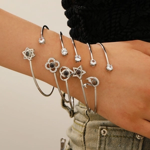 Détail de bracelets de projection argentés avec motifs cœur et étoile sur le poignet