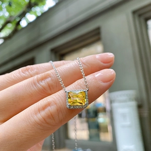 Macro view of silver necklace featuring a square yellow zircon pendant with halo setting