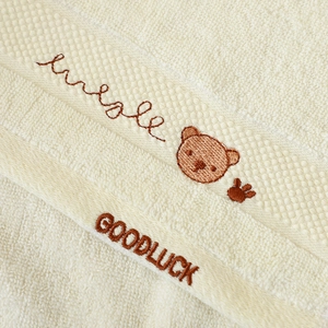 Close-up of soft cotton kids towel featuring brown bear embroidery and terry texture